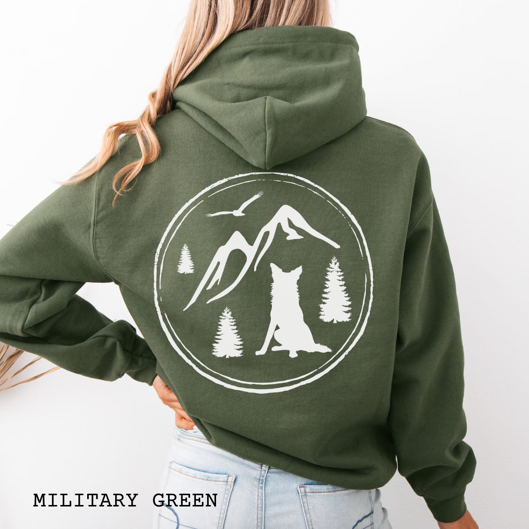 Person wearing a Military Green Border Collie back print hoodie featuring a vintage-style mountain, pine tree, and Border Collie silhouette back print for hiking enthusiasts, outdoor dog lovers, and Border Collie owners.