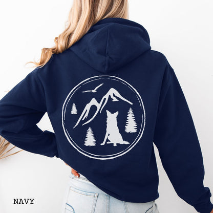 Person wearing a Navy blue Border Collie back print hoodie featuring a vintage-style mountain, pine tree, and Border Collie silhouette back print for hiking enthusiasts, outdoor dog lovers, and Border Collie owners.