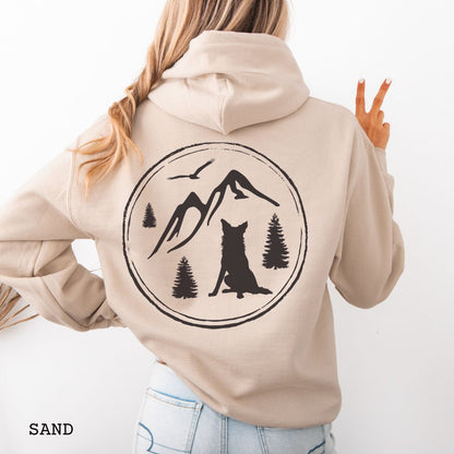 Person wearing a Sand colored Border Collie back print hoodie featuring a vintage-style mountain, pine tree, and Border Collie silhouette back print for hiking enthusiasts, outdoor dog lovers, and Border Collie owners.