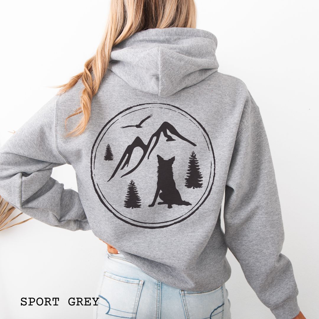 Person wearing a Sport Grey Border Collie back print hoodie featuring a vintage-style mountain, pine tree, and Border Collie silhouette back print for hiking enthusiasts, outdoor dog lovers, and Border Collie owners.