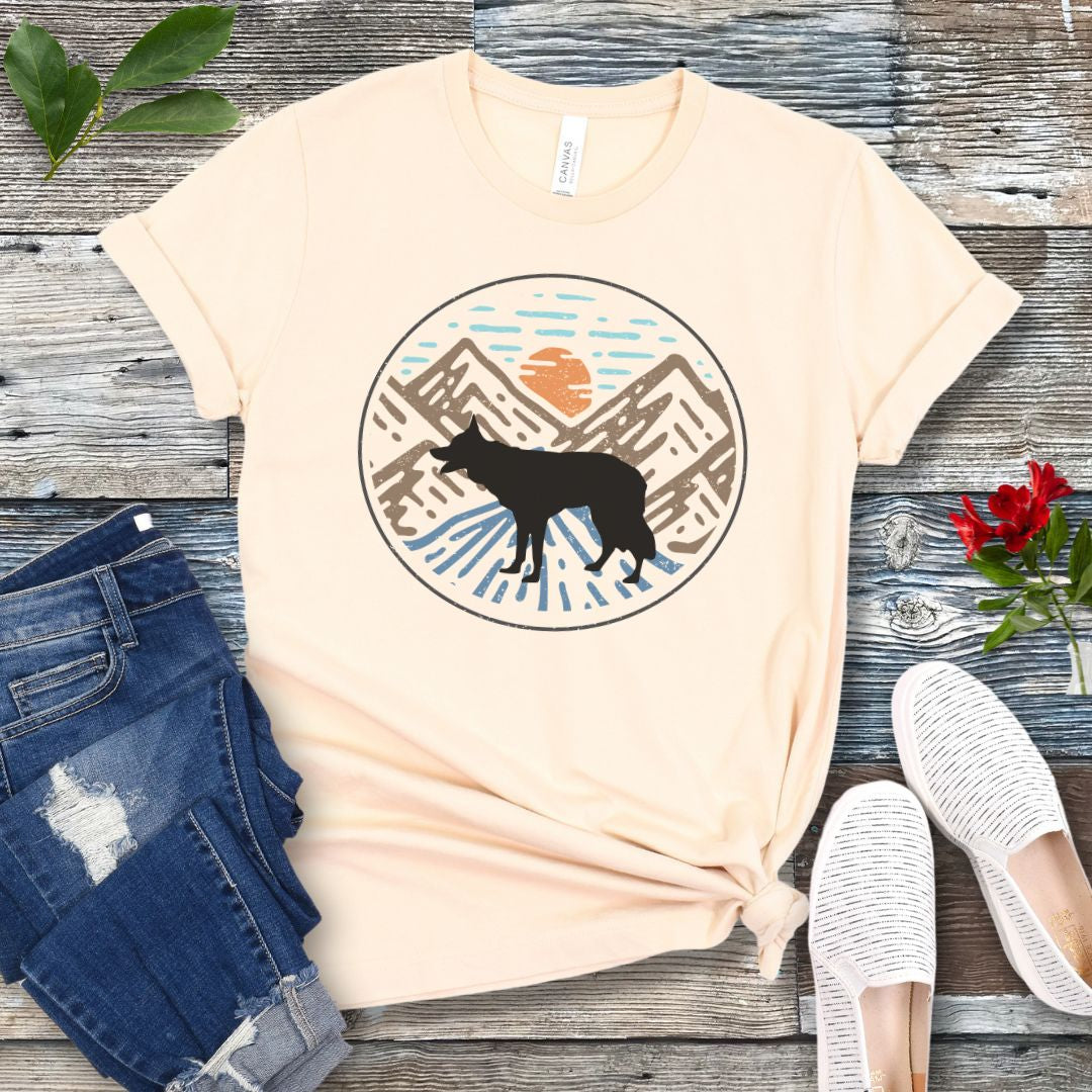 Beige t-shirt with a Border Collie in a vintage style mountain scene at sunset, shown on a wooden surface with jeans and shoes.