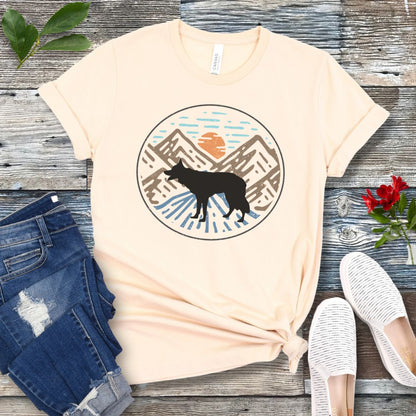 Beige t-shirt with a Border Collie in a vintage style mountain scene at sunset, shown on a wooden surface with jeans and shoes.
