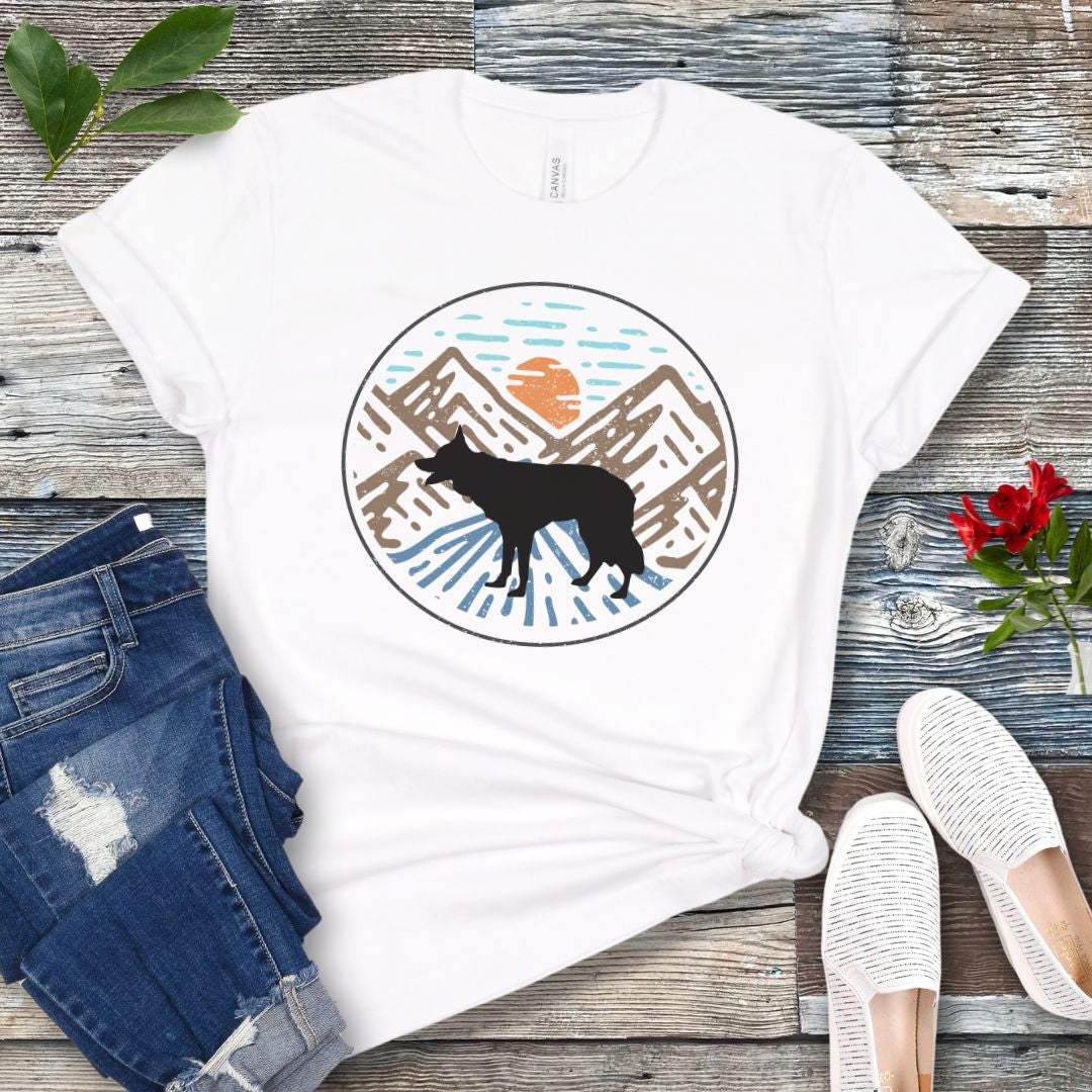 White t-shirt with a Border Collie dog in a vintage style mountain scene at sunset, shown on a wooden surface with jeans and shoes.