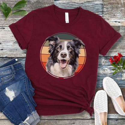 Maroon t-shirt for Border Collie lovers with a Border Collie face in a vintage style retro sunset graphic. Presented on a wooden surface with jeans and sneakers.