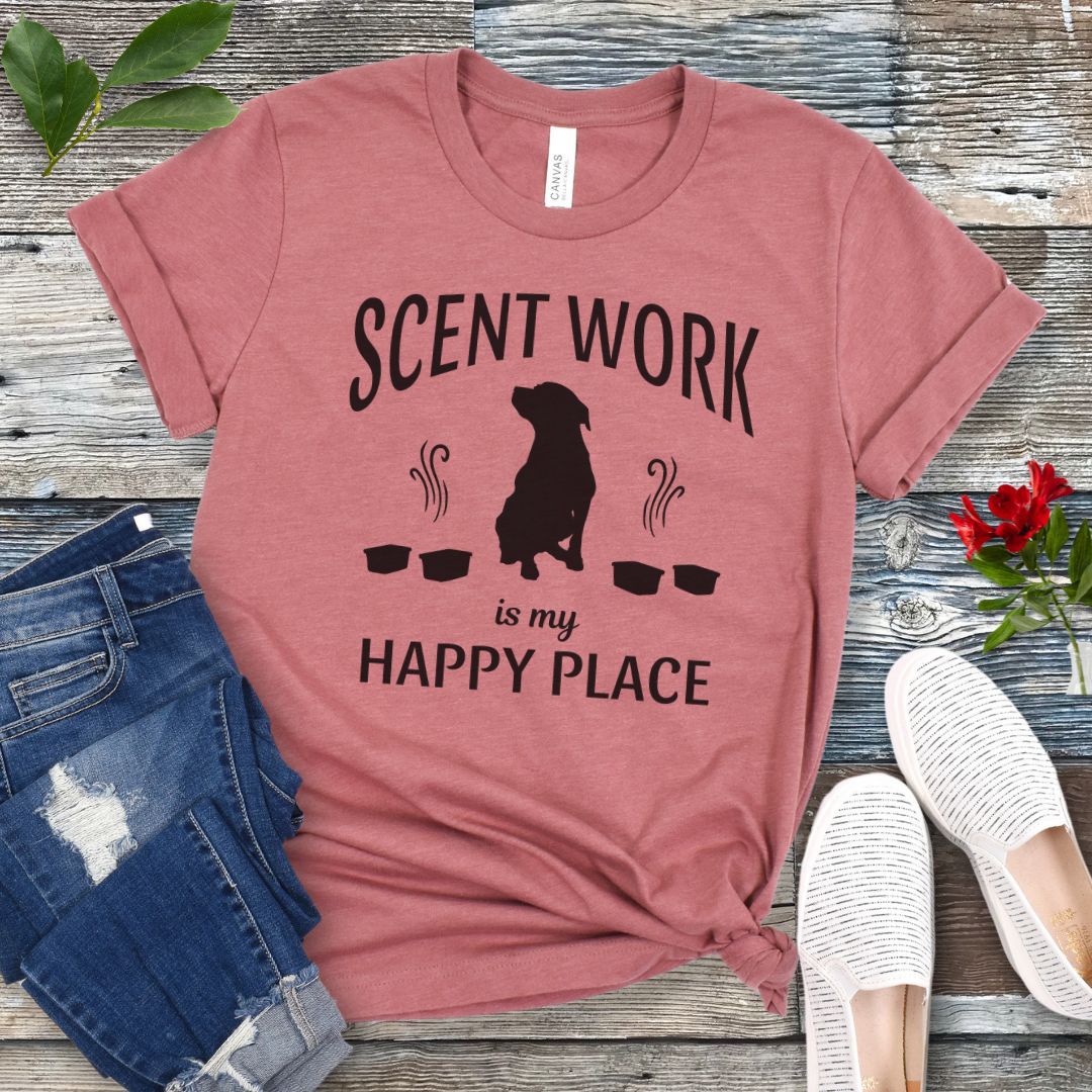 Mauve t-shirt with 'Scent Work is my Happy Place' text and dog silhouette on a wooden surface with jeans and shoes.