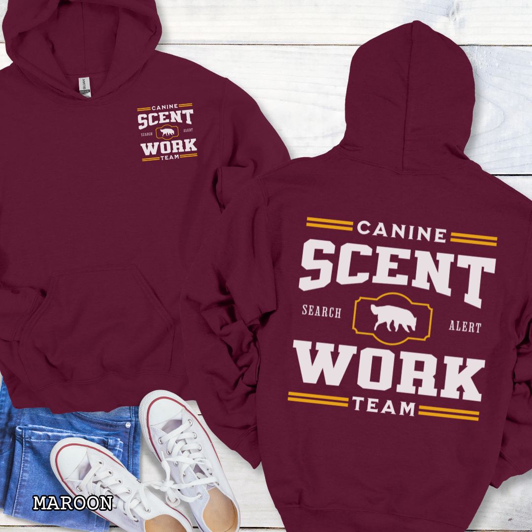 Maroon back print hoodie with 'Canine Scent Work Team' text on a wooden surface.