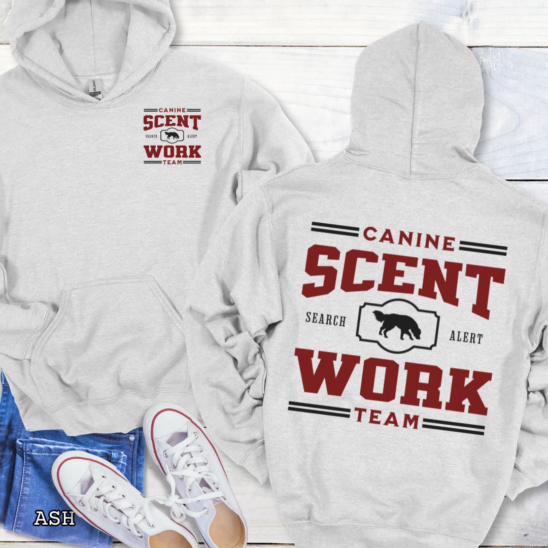 Light grey back print hoodie with 'Canine Scent Work Team' text on a wooden surface.