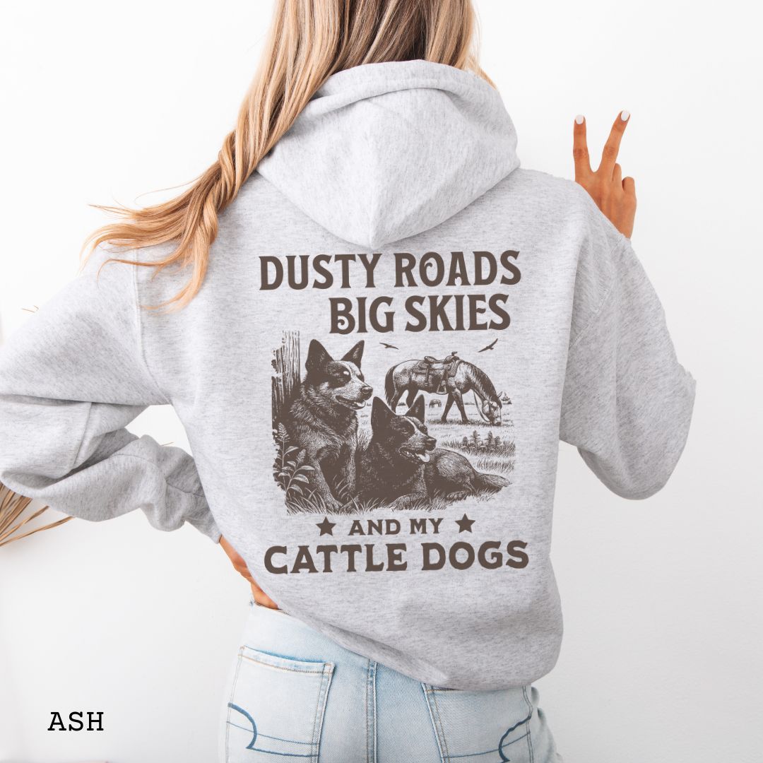 Back view of light grey Blue Heeler hoodie featuring a Western-style design with grazing horse, rustic fence, and Cattle Dog illustration; text reads “Dusty Roads, Big Skies, and My Cattle Dogs.”