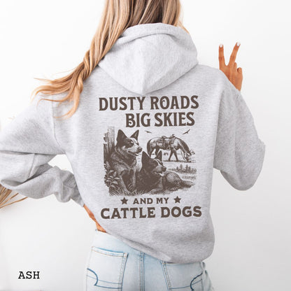 Back view of light grey Blue Heeler hoodie featuring a Western-style design with grazing horse, rustic fence, and Cattle Dog illustration; text reads “Dusty Roads, Big Skies, and My Cattle Dogs.”