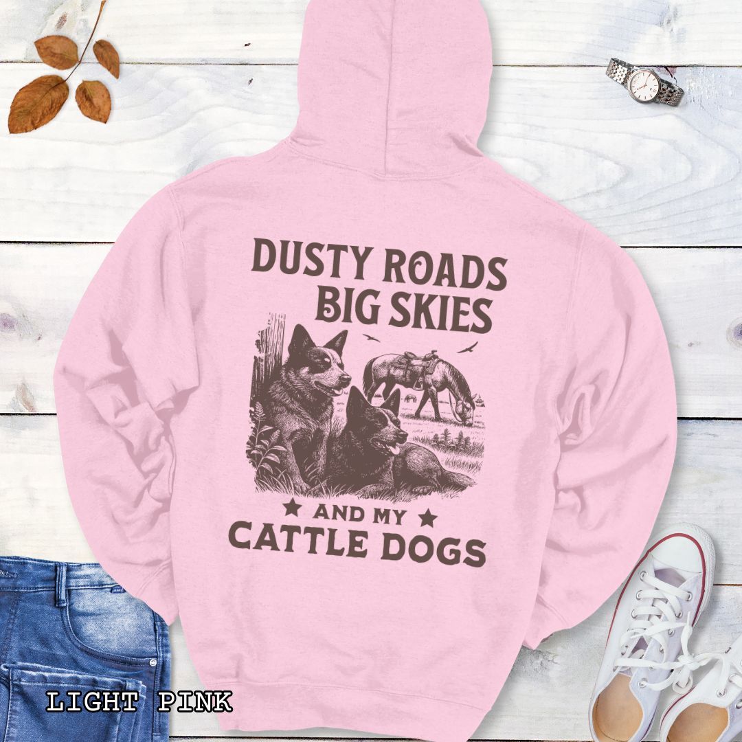 Back view of light pink Blue Heeler hoodie featuring a Western-style design with grazing horse, rustic fence, and Cattle Dog illustration; text reads “Dusty Roads, Big Skies, and My Cattle Dogs.”