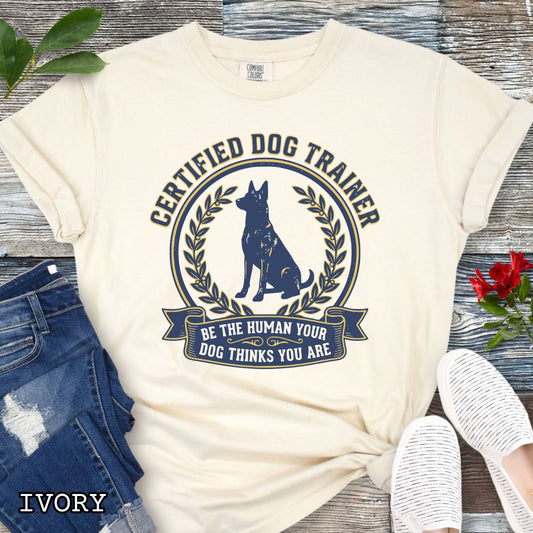 Ivory Comfort Colors t-shirt featuring a Certified Dog Trainer design with dog silhouette and Be the Human Your Dog Thinks You Are message, professional dog trainer shirt for canine trainers, obedience instructors, and dog training professionals.