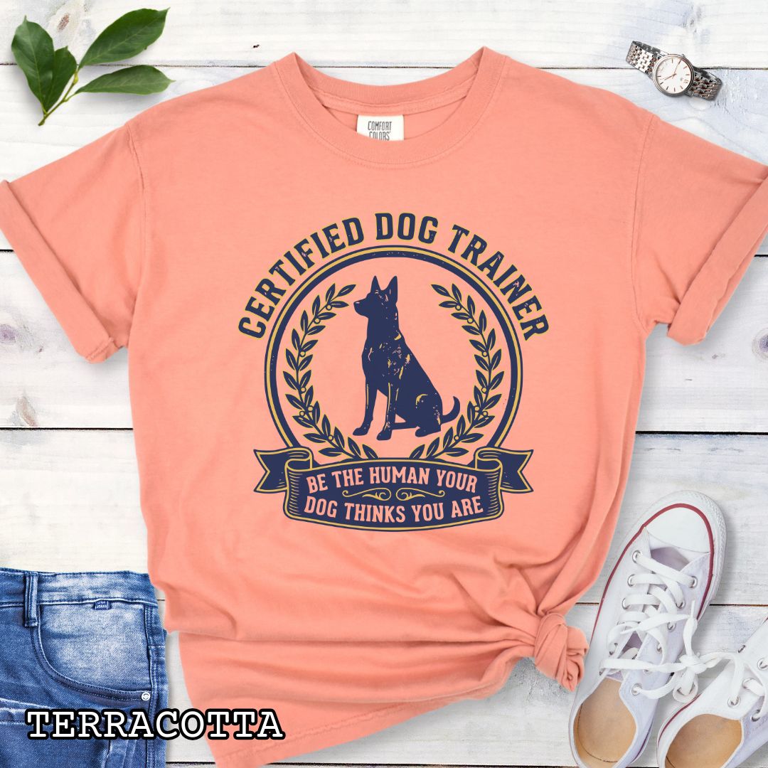 Orange Comfort Colors t-shirt featuring a Certified Dog Trainer design with dog silhouette and Be the Human Your Dog Thinks You Are message, professional dog trainer shirt for canine trainers, obedience instructors, and dog training professionals.