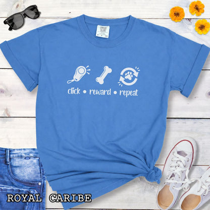 Royal blue Comfort Colors t-shirt featuring a Click Reward Repeat design with clicker, treat, and paw graphics for positive reinforcement dog trainers and clicker training enthusiasts.