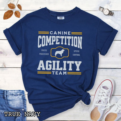 Navy Comfort Colors dog agility t-shirt with 'Canine Competition Agility Team' design and custom breed silhouette, presented on a wooden surface with denim shorts and a flower.