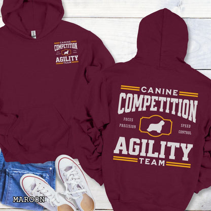 Maroon dog agility hoodie with 'Canine Competition Agility Team' text and custom breed silhouette, presented graphics on a wooden surface.