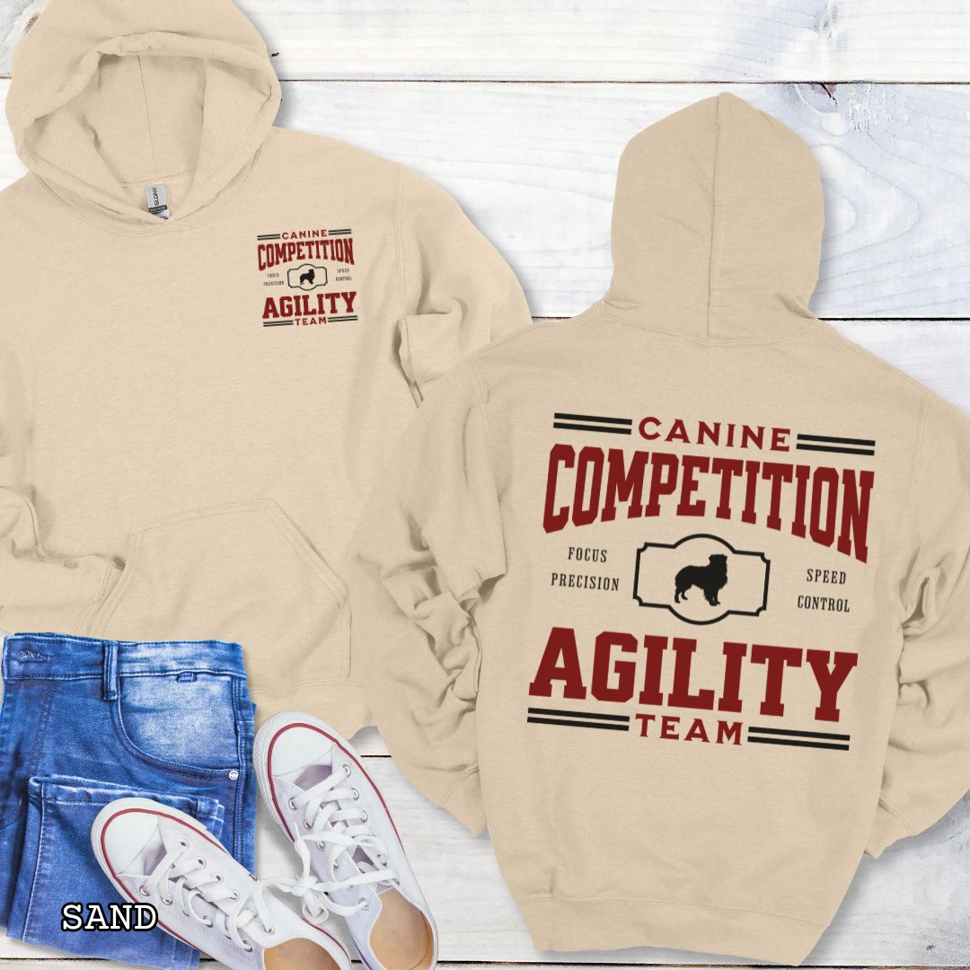 Beige dog agility hoodie with 'Canine Competition Agility Team' text and custom breed silhouette, presented graphics on a wooden surface.