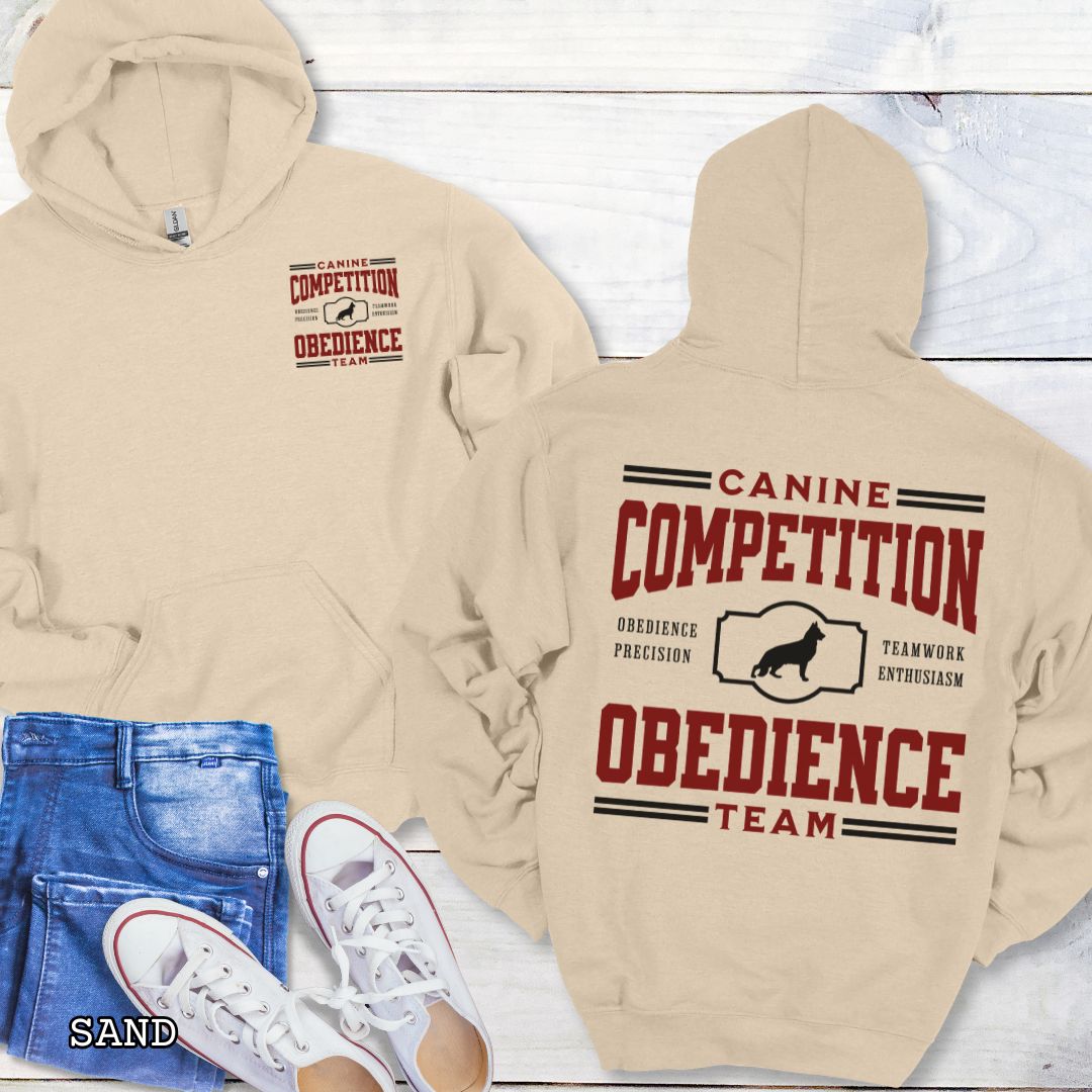 Beige dog obedience back print hoodie with 'Canine Competition Obedience Team' text and custom breed silhouette, presented on a wooden surface with denim jeans and a flower.
