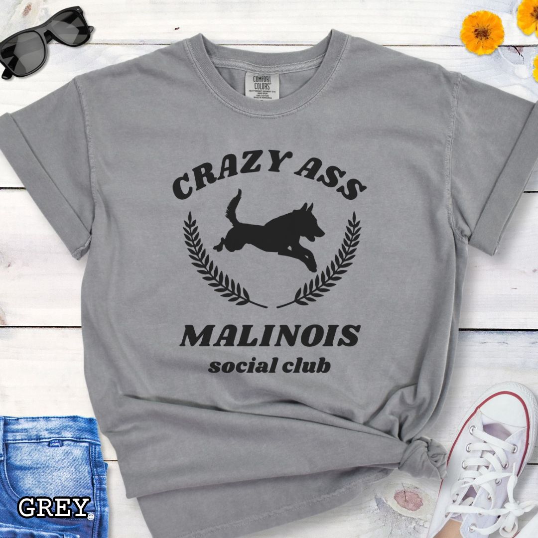 Grey Comfort Colors t-shirt with funny Crazy Ass Malinois Social Club design with jumping Belgian Malinois silhouette, perfect gift for Malinois owners, dog trainers, K9 handlers, working dog fans, and protection sport enthusiasts.