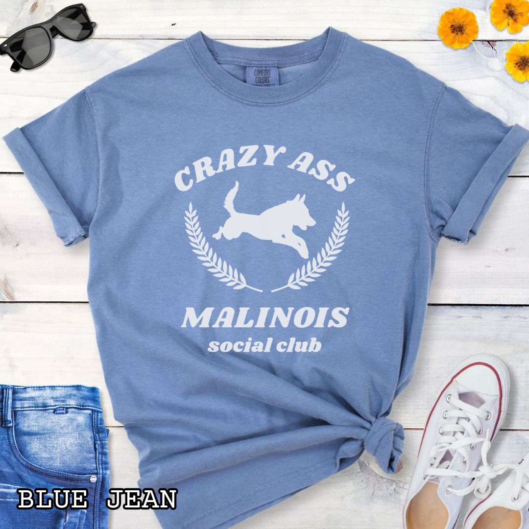 Blue Comfort Colors t-shirt with funny Crazy Ass Malinois Social Club design with jumping Belgian Malinois silhouette, perfect gift for Malinois owners, dog trainers, K9 handlers, working dog fans, and protection sport enthusiasts.