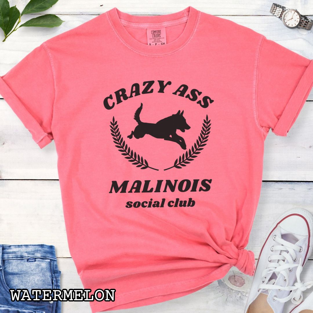 Pink Comfort Colors t-shirt with funny Crazy Ass Malinois Social Club design with jumping Belgian Malinois silhouette, perfect gift for Malinois owners, dog trainers, K9 handlers, working dog fans, and protection sport enthusiasts.