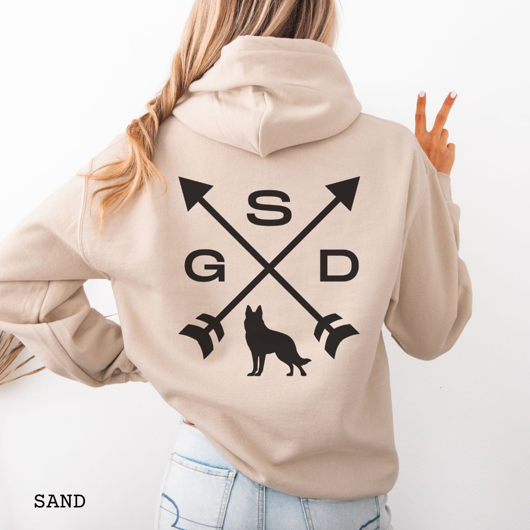 Back view of a beige unisex hoodie with a crossed arrows design with 'GSD' text and a German Shepherd silhouette, worn by a person.