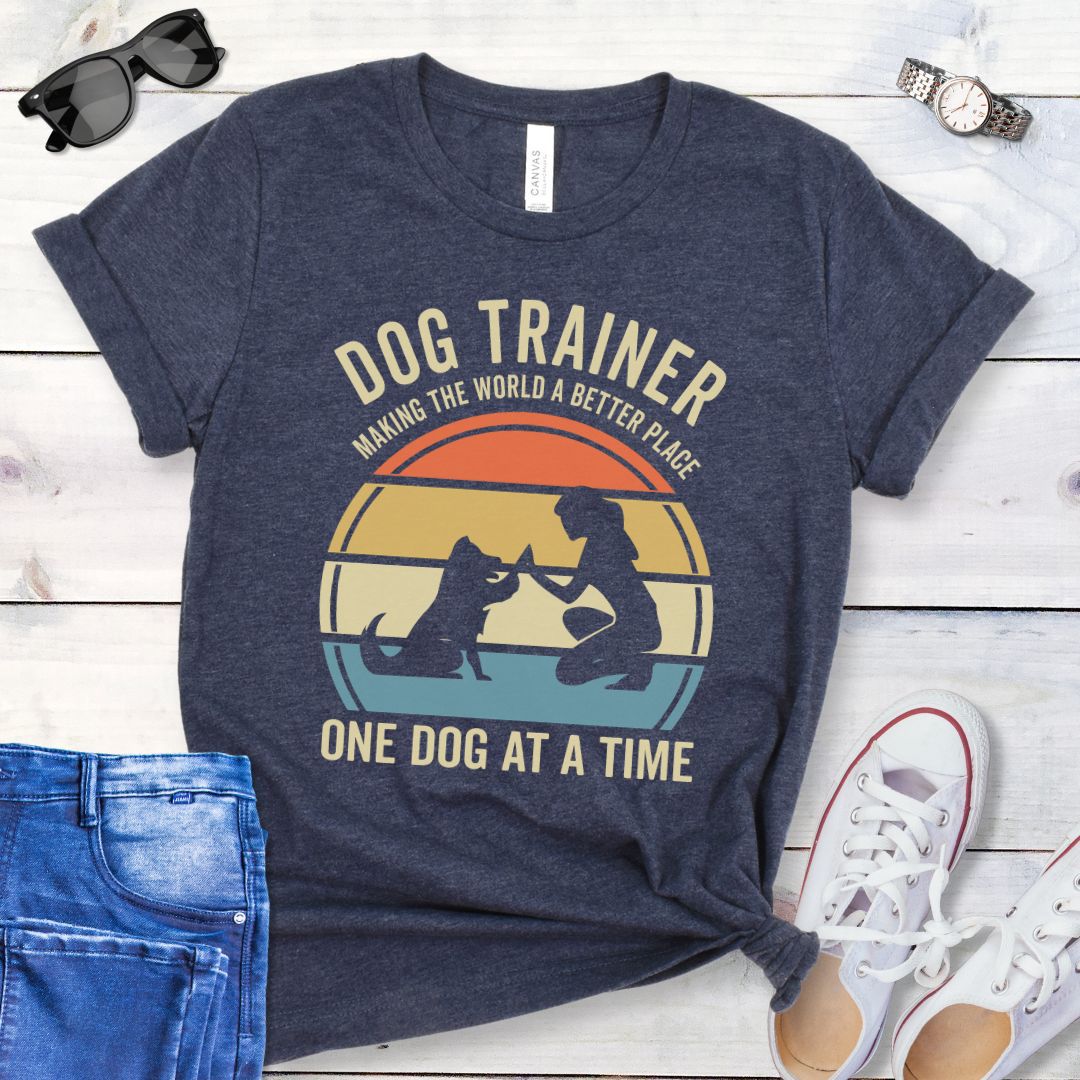 White t-shirt with 'Dog Trainer' graphic and positive quote on a wooden surface with jeans and shoes.