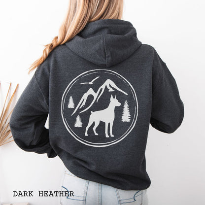 Dark grey Doberman Pinscher hoodie featuring a bold vintage-style back print with Doberman silhouette, mountains, pine trees, perfect gift for hiking and outdoorsy Doberman dog lovers.