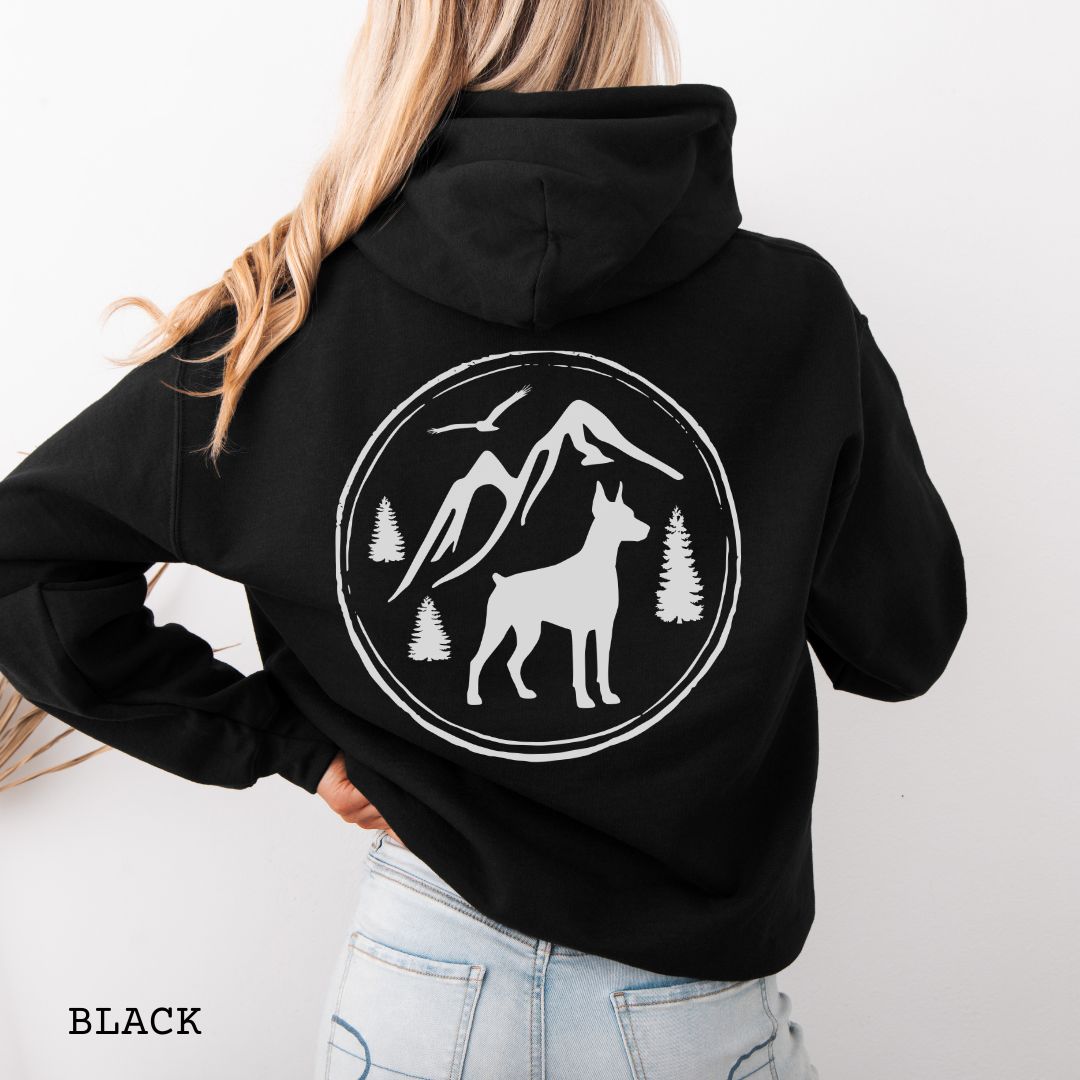 Black Doberman Pinscher hoodie featuring a bold vintage-style back print with Doberman silhouette, mountains, pine trees, perfect gift for hiking and outdoorsy Doberman dog lovers.