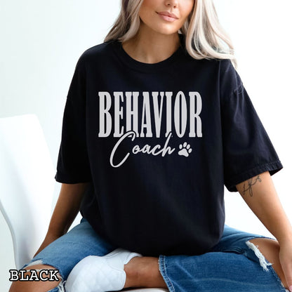 Person wearing a black dog training t-shirt with 'Behavior Coach' text and paw print.
