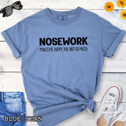 Blue Comfort Colors t-shirt with 'NOSEWORK MAKES ME HAPPY. YOU NOT SO MUCH.' text, shown on a wooden surface with denim jeans and a flower.