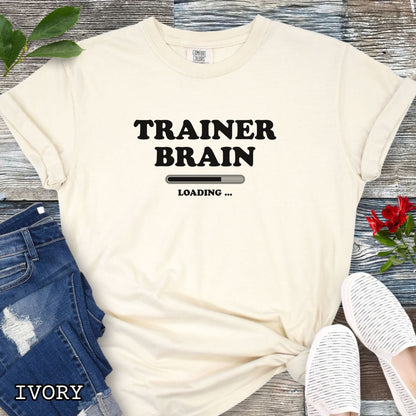 A beige Comfort Colors unisex t-shirt for dog training enthusiasts, featuring a bold  text design that reads 'TRAINER BRAIN' above a loading bar and 'LOADING . Makes a perfect funny dog trainer gift.