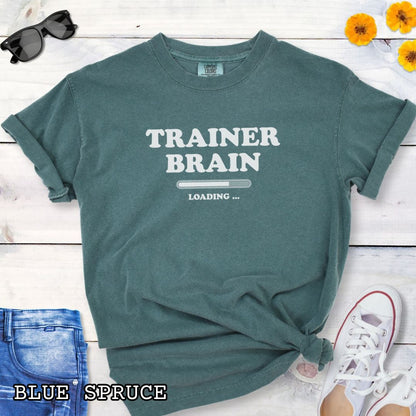 A green Comfort Colors unisex t-shirt for dog training enthusiasts, featuring a bold text design that reads 'TRAINER BRAIN' above a loading bar and 'LOADING . Makes a perfect funny dog trainer gift.