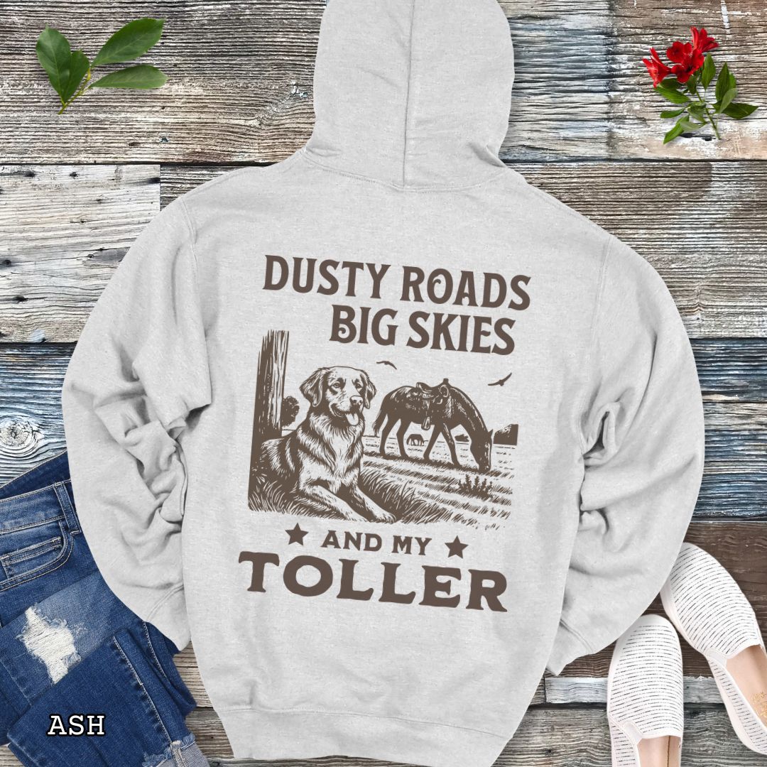 Back view of a light grey hoodie featuring a Western-style design with grazing horse, rustic fence, and a Duck Tolling Retriever illustration; text reads “Dusty Roads, Big Skies, and My Toller.”