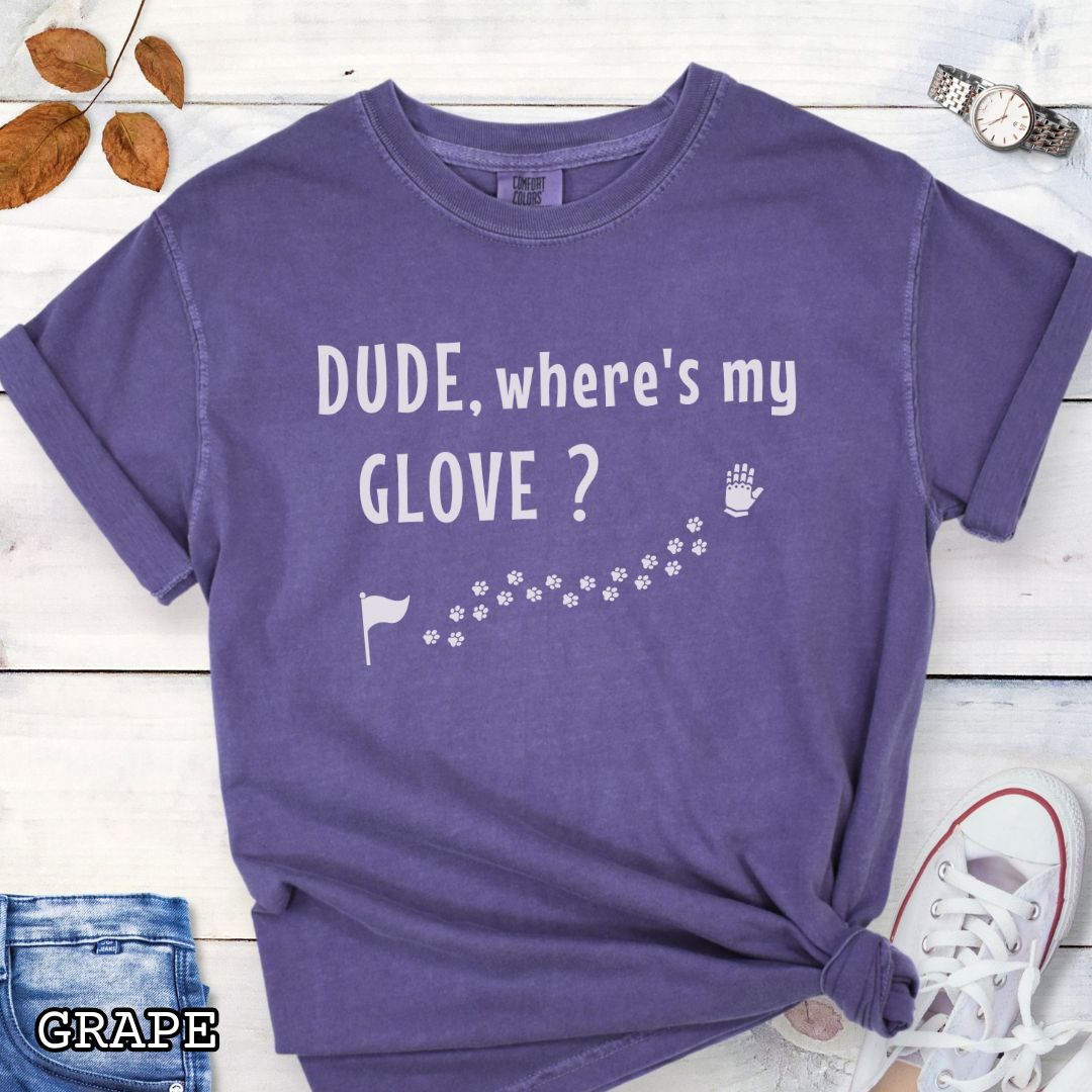 Purple tracking dog t-shirt with flag, paw prints, and glove, and the text 'DUDE, where's my GLOVE?', presented on a wooden surface with accessories.