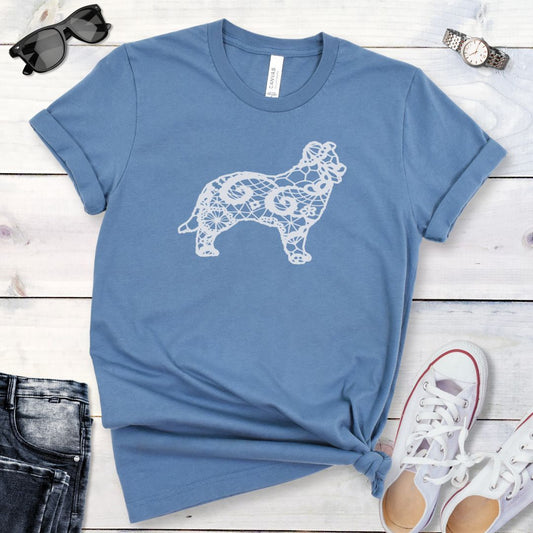 Blue t-shirt for Border Collie moms with lace-pattern filled Border Collie silhouette, shown on a wooden surface with accessories.