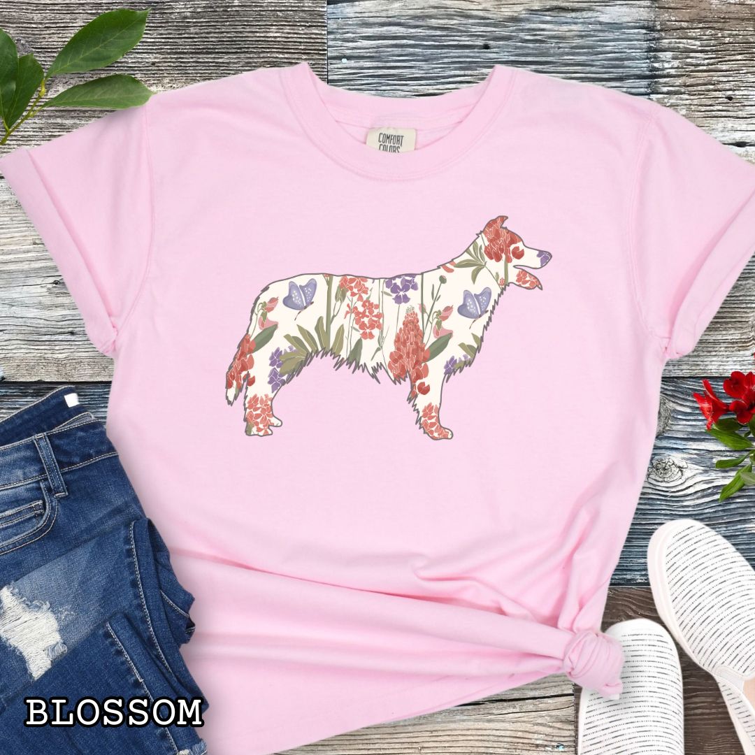 Pink Comfort Colors t-shirt with floral Border Collie dog design on a wooden surface with jeans and shoes.
