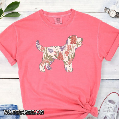 Watermelon Comfort Colors t-shirt with a floral-filled silhouette of a Doodle dog, accompanied by a pair of rolled-up blue jeans and a pair of white shoes on a wooden surface.