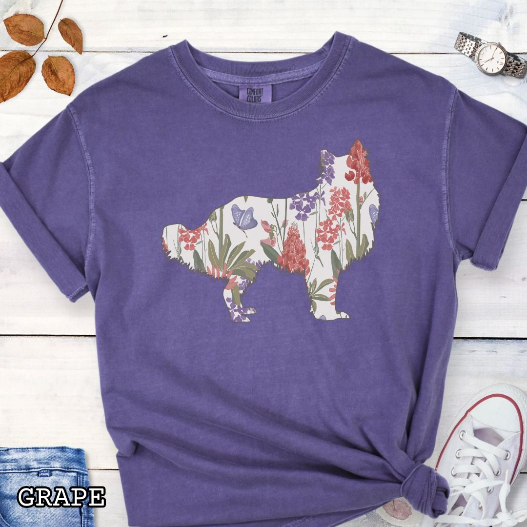 Purple Comfort Colors t-shirt with Rough Collie silhouette filled with floral pattern, presented on a wooden surface with jeans and shoes.