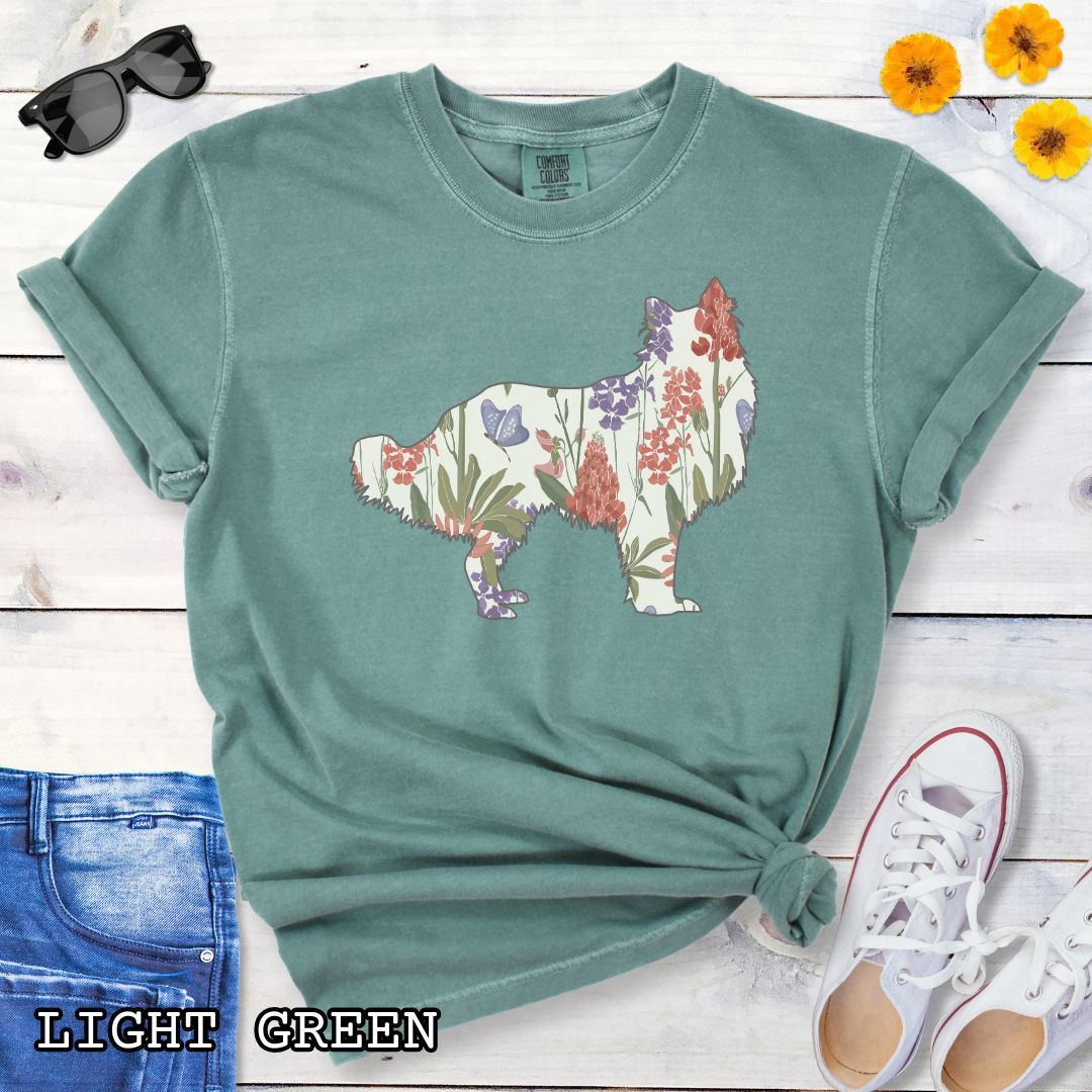 Green Comfort Colors t-shirt with Rough Collie silhouette filled with floral pattern, presented on a wooden surface with jeans and shoes.