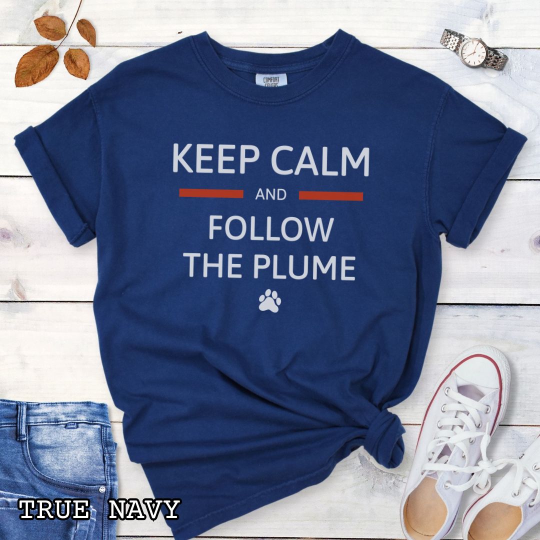 Dark blue Comfort Colors for k9 scent work trainers t-shirt with 'Keep Calm and Follow the Plume' text on a wooden surface with shoes and jeans.