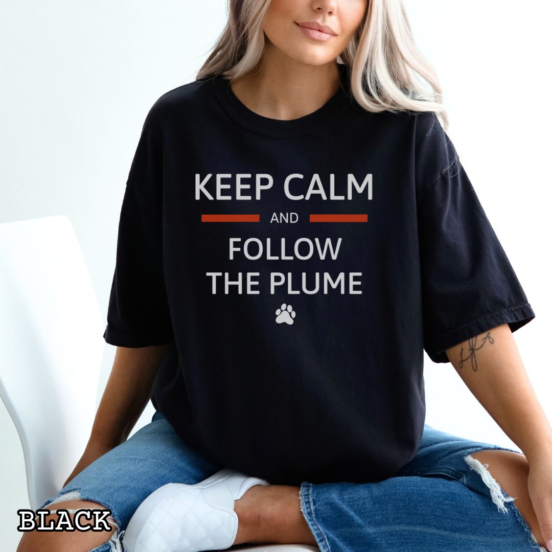 Black Comfort Colors for k9 scent work trainers t-shirt with 'Keep Calm and Follow the Plume' text on a wooden surface with shoes and jeans.