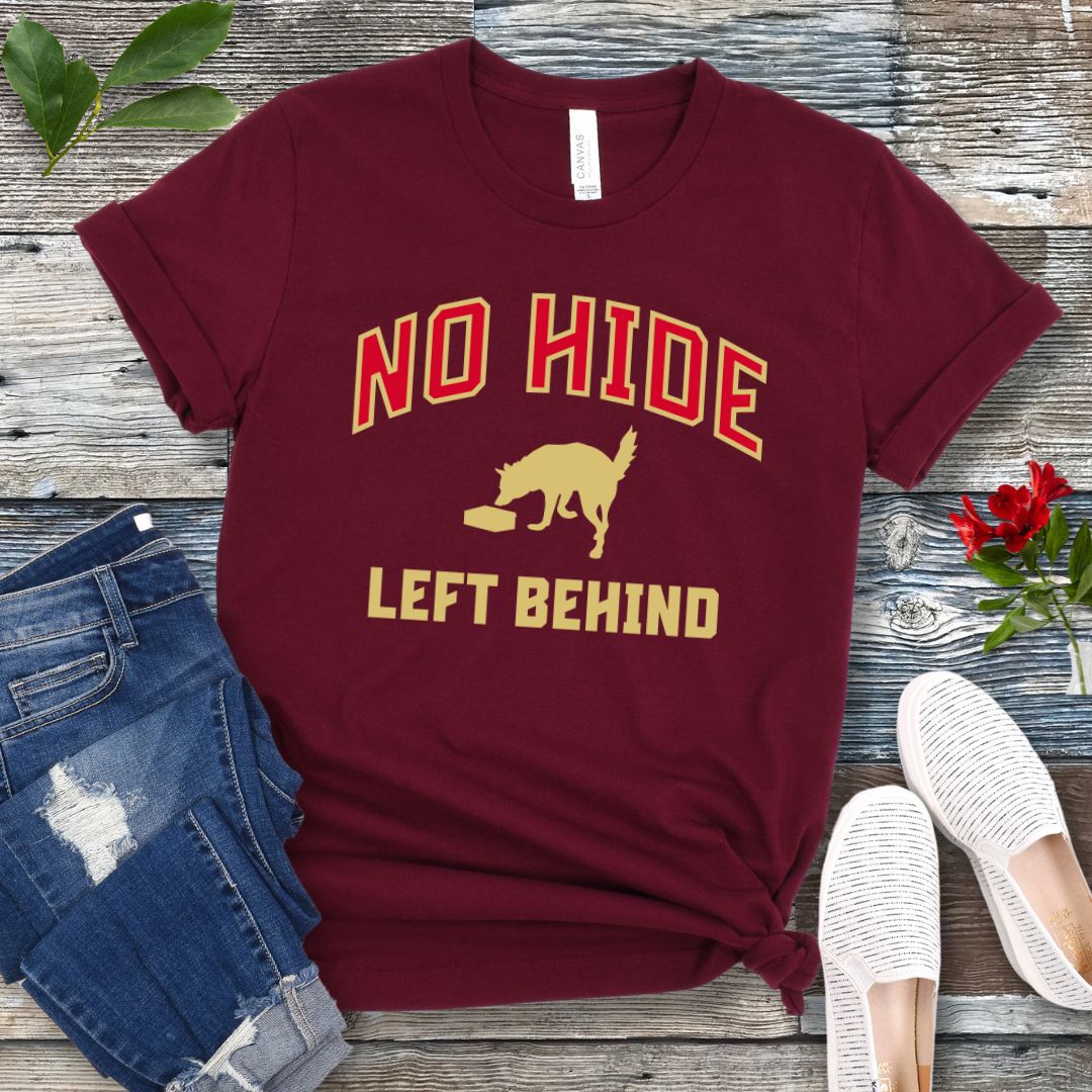 Maroon canine scent work t-shirt with 'No Hide Left Behind' text and sniffing dog graphic on a wooden surface with jeans and shoes.