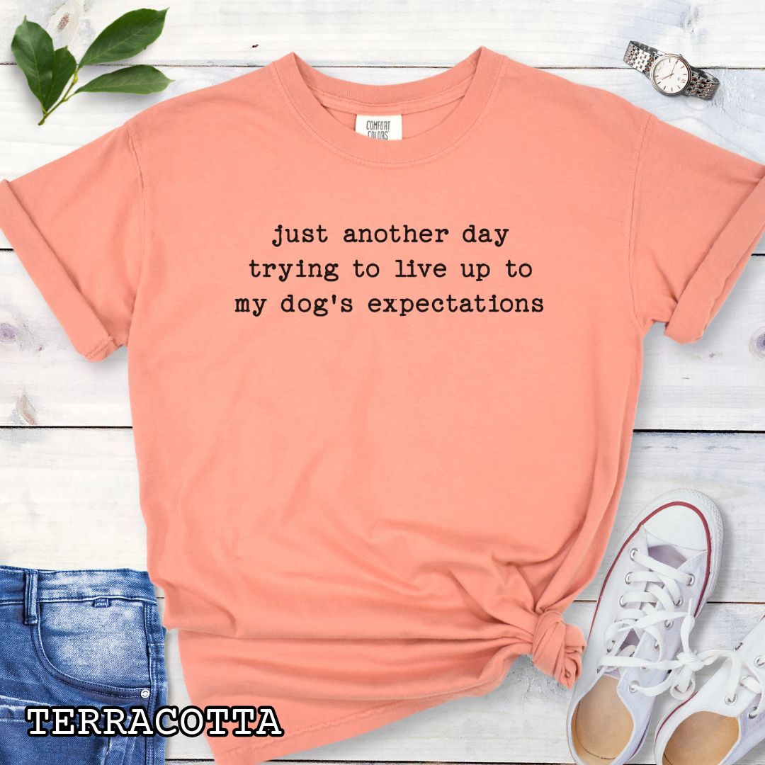 Orange Comfort Colors t-shirt featuring funny sarcastic 'Just Another Day Trying to Live Up to My Dog’s Expectations' quote, perfect humorous dog lover shirt for dog moms, dog dads, and pet parent gifts.