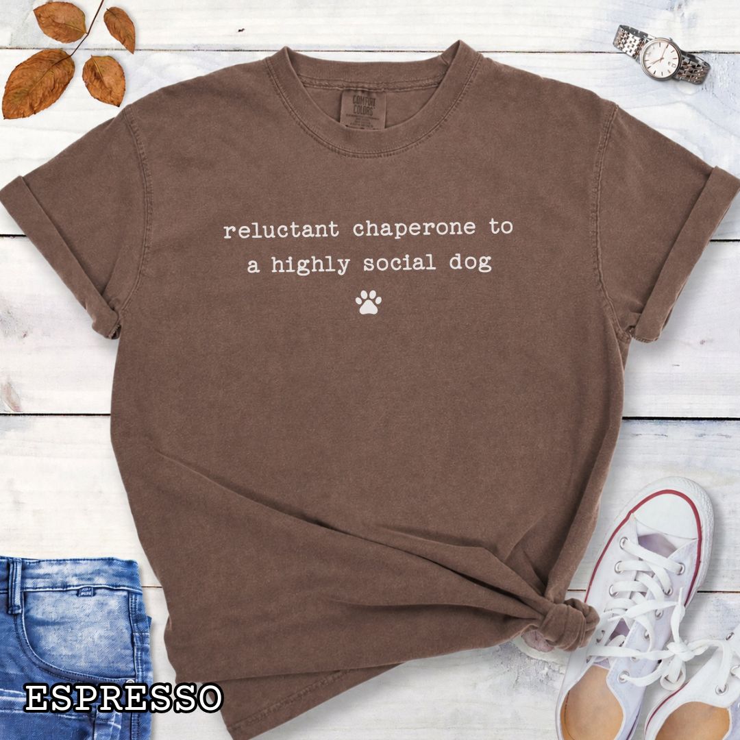 Brown Comfort Colors t-shirt featuring Reluctant Chaperone to a Highly Social Dog funny quote design, perfect humorous dog owner shirt for introvert dog lovers, dog moms, dog dads, and pet parent gifts.