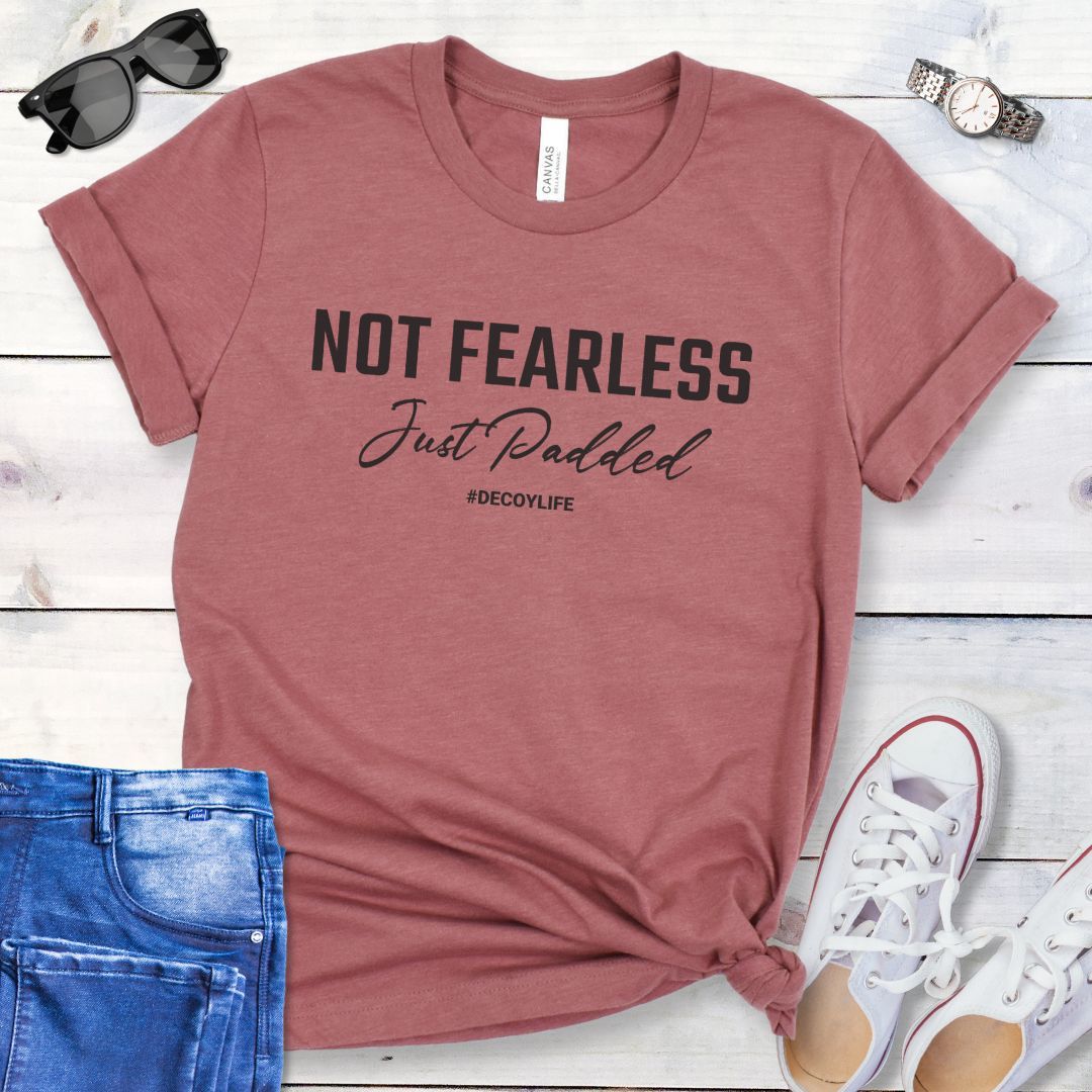 Mauve K9 helper t-shirt with 'Not Fearless Just Padded, #decoylife' text on a wooden surface with jeans and shoes.