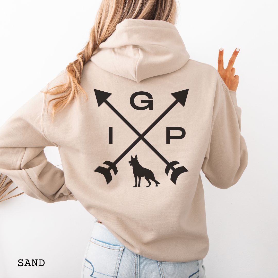 Back view of a beige Schutzhund/IGP hoodie with crossed arrows design with 'IGP' text and German Shepherd silhouette on the back, worn by a person.