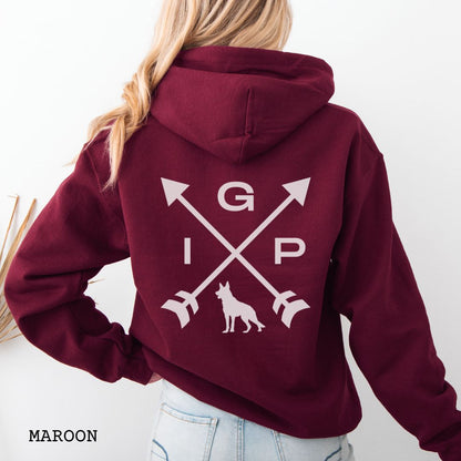 Back view of a maroon Schutzhund/IGP hoodie with crossed arrows design with 'IGP' text and German Shepherd silhouette on the back, worn by a person.