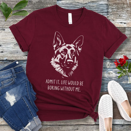 Maroon t-shirt for German Shepherd lovers with with Shepherd dog face graphic and humorous text 'Admit it. Life would be boring without me'. Shown on a wooden surface with accessories.