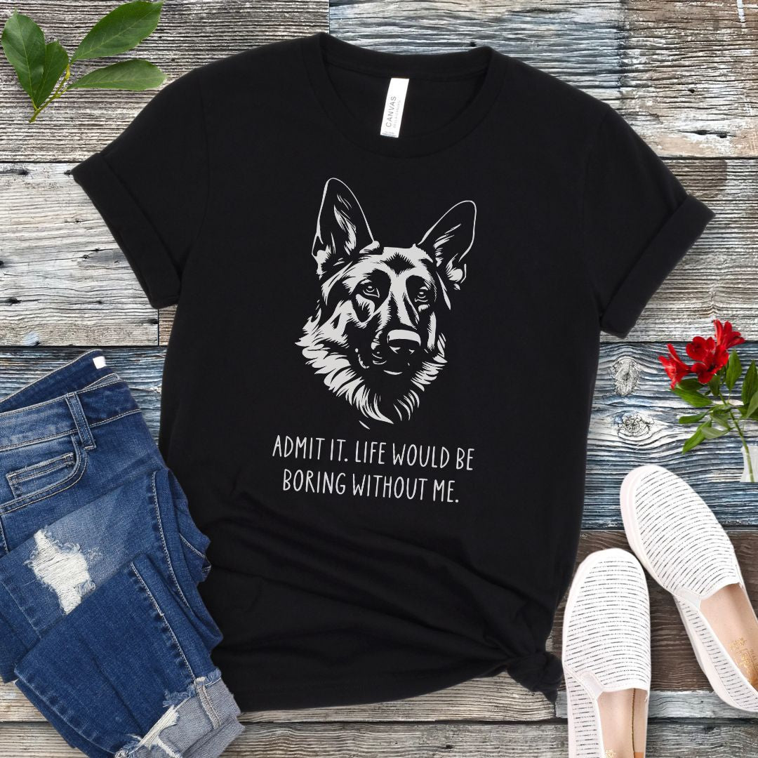 Black t-shirt for German Shepherd lovers with with Shepherd dog face graphic and humorous text 'Admit it. Life would be boring without me'. Shown on a wooden surface with accessories.