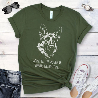 Military green t-shirt for German Shepherd lovers with with Shepherd dog face graphic and humorous text 'Admit it. Life would be boring without me'. Shown on a wooden surface with accessories.